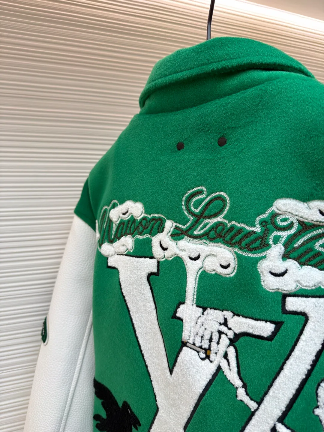 LOUIS VUITTON Loose long-sleeved baseball jersey with monogram pattern ●Original version: Purchased and developed for 29999 ●Item number: 1682254-C10 ●Fabric: cotton fabric ●Technology: embroidery production ●Color: green ●Version: fitted version ●Weight: about 1145 grams ●Size: 46-48-50-52 ●Description: The main body of this Louis Vuitton baseball jacket is made of high-count wool blended fabric. It has been processed by raising and carding processes. The fabric has a full velvety feel and is crisp and stylish. The green base color is made of worsted dyeing process. The color is pure and not easy to fade. The sleeves are spliced ​​with custom pebbled artificial leather, which has been embossed and softened. The texture is natural, flexible to the touch, and is scratch-resistant and wear-resistant. The letters and patterns decorated on the body are made of terry embroidery + appliqué embroidery composite technology. The terry embroidery coils are fluffy and three-dimensional, and the edges of the appliqué embroidery are overlocked to ensure accurate pattern splicing. The handwritten text is made using flat embroidery technology, with fine stitches and clear fonts. The placket is made of custom-made mother-of-pearl buttons, which are hand-polished and polished to have a warm luster; the ribbed neckline and hem are made of spandex blended material, which has good resilience and is not easy to loosen. The overall design uses three-dimensional tailoring and hand-sewing techniques to integrate a variety of materials and embroidery techniques to fully demonstrate the essence of haute couture garments. The overall wiring is straight and delicate, the fabric is comfortable and soft, and the color is consistent without color difference. It can be matched with the same style to create a fashionable look and control various occasions. Customized accessories, complete with three standards, same style for men and women!